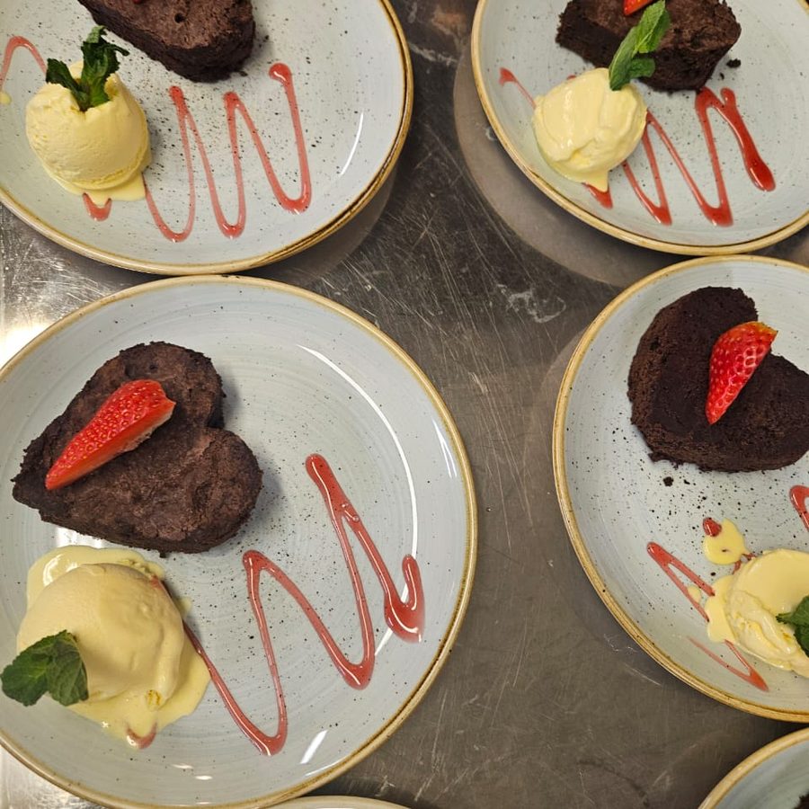 Chocolate desserts plated with cream and strawberry coulis